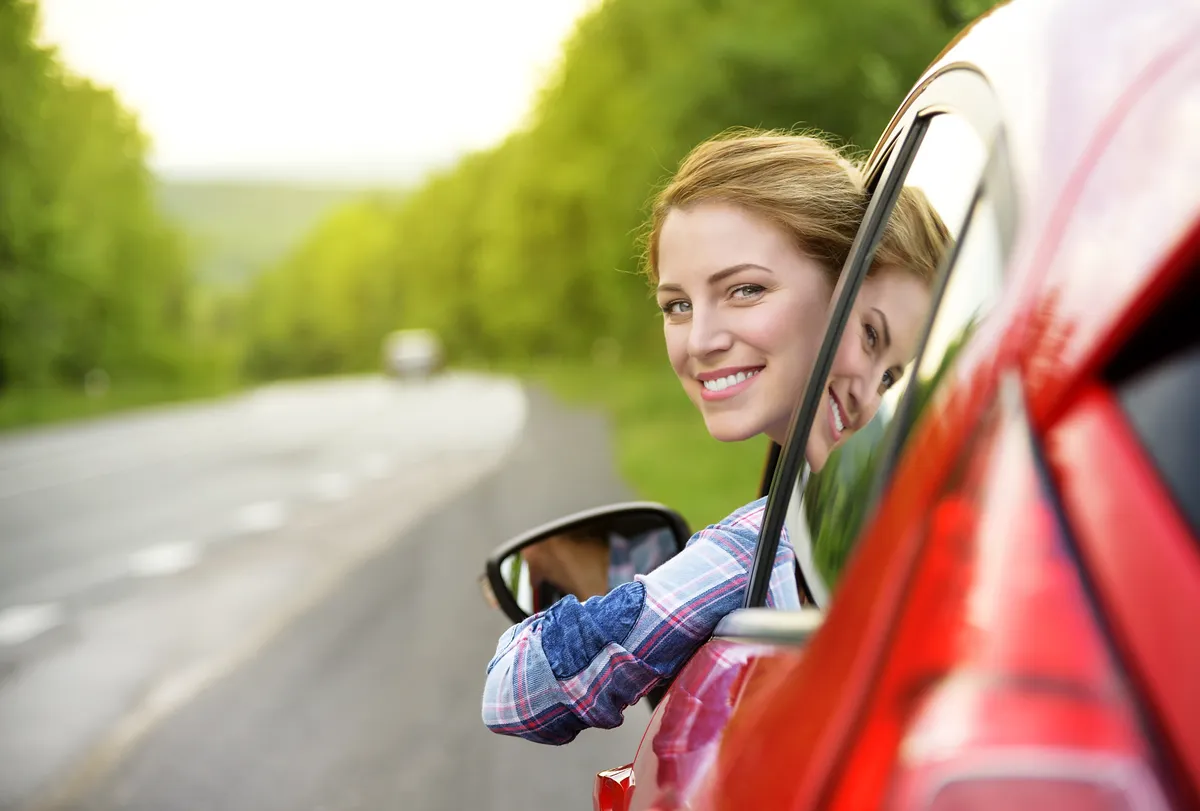 Blije vrouw in rode auto